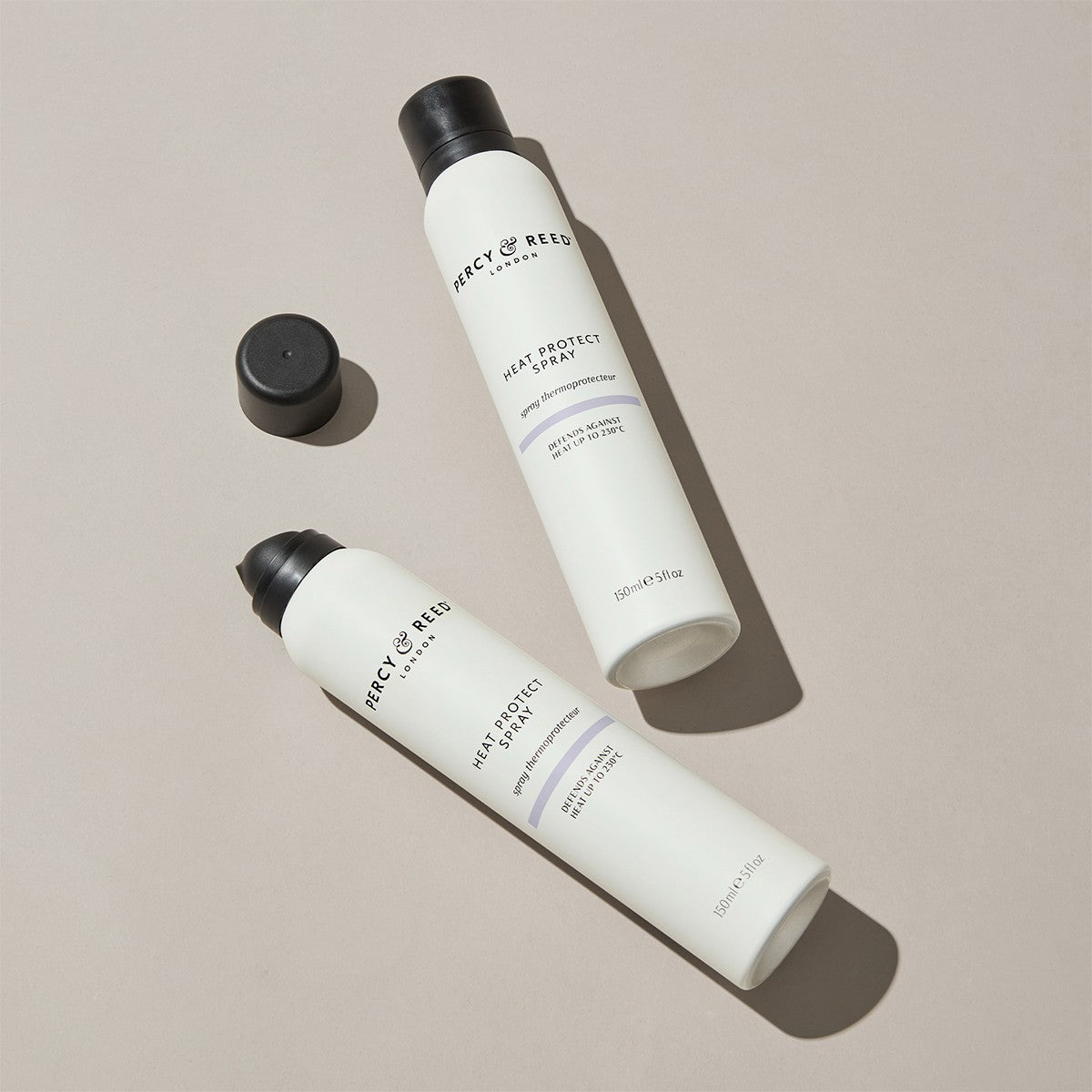 Product shot of two bottles of Percy & Reed Heat Protect Spray for hair